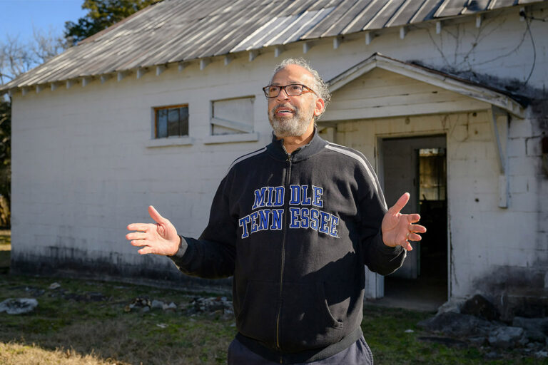 Alum standing in front of old school