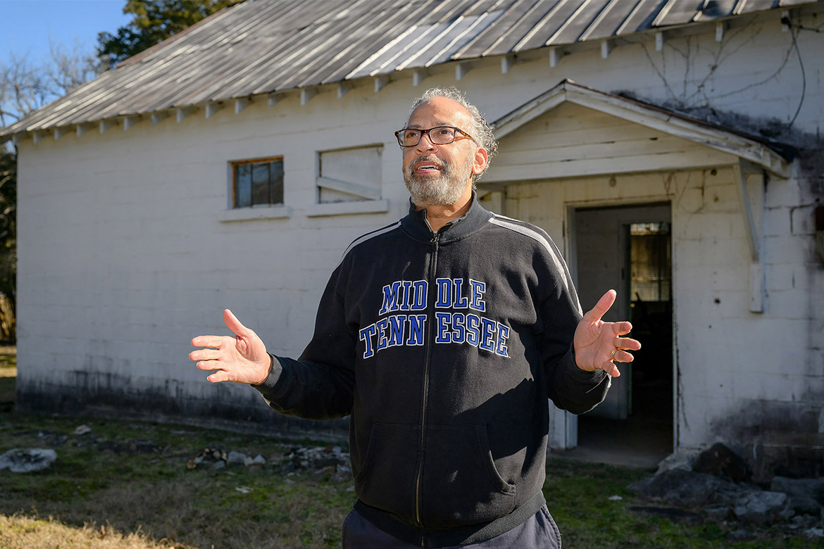 Alum standing in front of old school